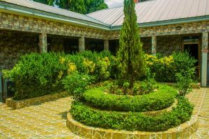 a garden with trees and bushes in front of a building at Ruk's Hotel in Tamale