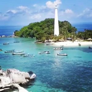 a lighthouse on a beach with boats in the water at Belitung Backpacker in Tanjungpandan