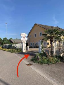 uma seta vermelha apontando para um edifício numa rua em La terrasse du parc em Marckolsheim