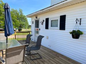 a patio with a table and chairs and an umbrella at The Coastal Country House in New Brunswick in Cape Tormentine