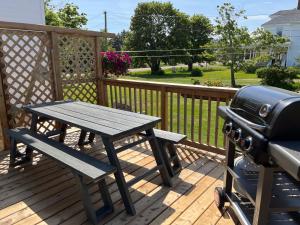 a picnic table and a grill on a deck at The Coastal Country House in New Brunswick in Cape Tormentine