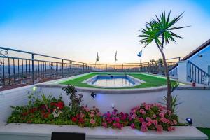 a swimming pool with flowers and a palm tree at Hotel Sierra de Huesa in Huesa