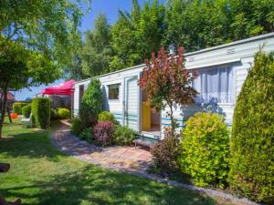 a small white caravan in a yard with bushes at Domki u Ewy in Wrzosowo