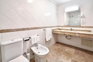 uma casa de banho com um WC, um lavatório e um espelho. em Galeria Suite Hotel em Aveiro