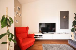Summer Breeze apartment في زادار: غرفة معيشة فيها كرسي احمر وتلفزيون