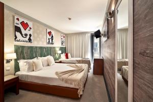 a hotel room with two beds and a television at Galeria Suite Hotel in Aveiro