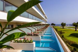 an external view of a building with a pool and plants at Ammoa Luxury Hotel & Spa Resort in Nikiti