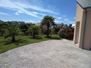 a gravel driveway next to a house with palm trees at Chambre agréable au calme in Saint-Hilaire-Petitville