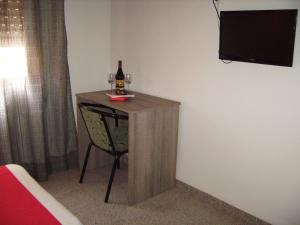 a small table with a bottle of wine and a chair at Pension Miami in Almazora