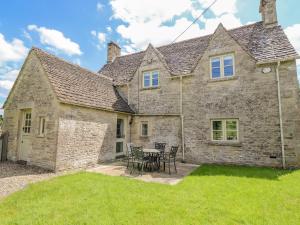 an old stone house with a table and chairs at No 1 Eastington in Cheltenham