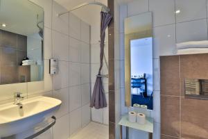 ein Badezimmer mit Waschbecken und Spiegel in der Unterkunft Hôtel restaurant Kyriad Fréjus in Fréjus + 176 Fotos