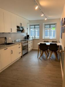 a kitchen with white cabinets and a table and chairs at Stadtquartier 1 EG in Bredstedt