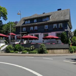 un restaurante con sombrillas rojas frente a un edificio en Land-gut Hotel zur Brücke garni, en Drolshagen