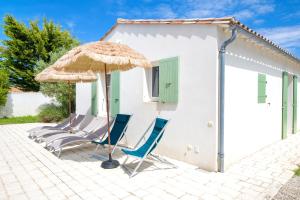 a group of chairs and an umbrella and a house at "MORANDE" grande maison avec Piscine Chauffée in La Noue