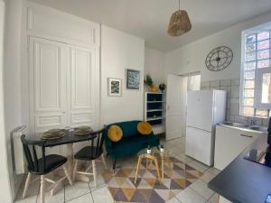 a kitchen with a table and a refrigerator at l'Emeraude de Calais - Confort et central in Calais