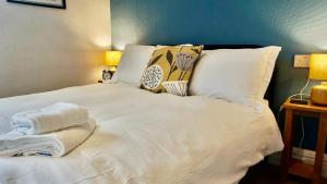 uma cama branca com almofadas e toalhas em Greystoke House em Keswick