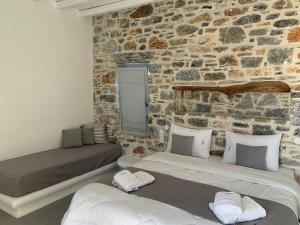 two beds in a room with a stone wall at Thomas Villas on the beach Katapola in Katapola