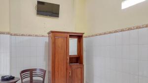 una camera con sedia e armadietto in legno di Hotel Shinta 1 near Stasiun Kertosono Mitra RedDoorz a Pelem