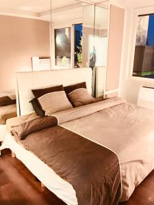a large bed in a bedroom with two windows at Appartement Grande Terrasse Vue Tour Eiffel in Paris