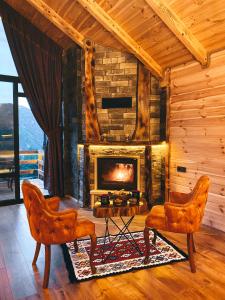a living room with a fireplace in a log cabin at ZirvedeKal Suit Otel in Çamlıhemşin
