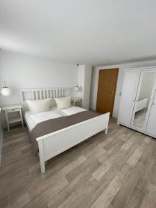 a bedroom with a large white bed and wooden floors at Ferienwohnung Keil in Bad Schandau