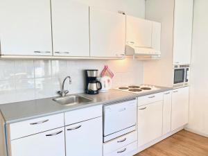 una cocina blanca con armarios blancos y fregadero en Badhotel 316, en Callantsoog