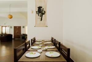 a long wooden table with chairs and plates on it at SaffronStays WellBeingVilla, Wayanad in Vythiri