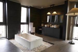 a large bathroom with a white tub and black tiles at Hotel Lacky Daejeon in Daejeon