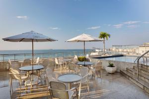une terrasse avec des tables et des chaises ainsi qu'une piscine dans l'établissement Windsor Palace Copacabana, à Rio de Janeiro