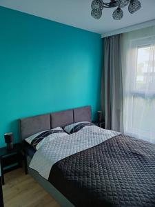 a bedroom with a bed with a blue wall at Apartament Letnicka, Nowy, 950m od morza in Gdańsk