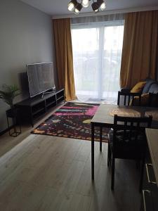 un soggiorno con TV, tavolo e sedie di Apartament Letnicka, Nowy, 950m od morza a Danzica