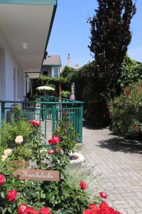 einen Garten mit roten Rosen und einem grünen Zaun in der Unterkunft Pension Daniela Steiner in Podersdorf am See