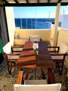 una mesa de madera en un balcón con vistas al océano en Virginia Pension, en Tinos