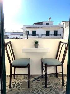 twee stoelen naast een tafel op een balkon bij Virginia Pension in Tinos Town