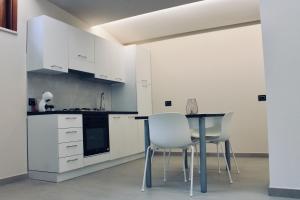 a kitchen with white cabinets and a table and chairs at Di Rosa Apartment in Avola