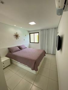 Carneiros Beach Resort Flat في تامانداري: غرفة نوم فيها سرير وتلفزيون