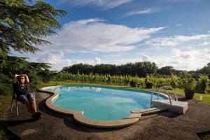 a man sitting in a chair next to a swimming pool at Vandenbeld Wines B&B in Minzac
