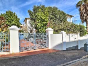 uma cerca branca em frente a uma casa com árvores em The Walden Suites em Cidade do Cabo