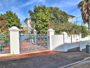 una cerca blanca frente a una casa con árboles en The Walden Suites, en Ciudad del Cabo