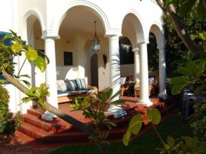 un porche de una casa blanca con sofá en The Walden Suites, en Ciudad del Cabo