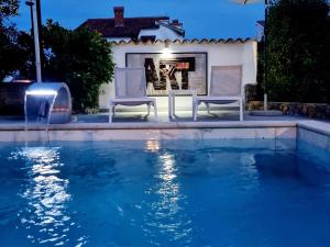 a swimming pool with two chairs and a fireplace at Villa Art House Krk in Krk