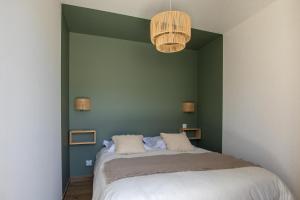 sypialnia z łóżkiem i zieloną ścianą w obiekcie Superbe appartement bord de mer w mieście Saint-Mandrier-sur-Mer