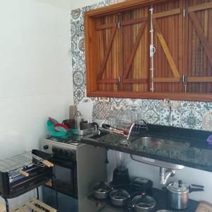 a kitchen with a sink and a stove with pots and pans at Pousada Epicurista in Capitólio