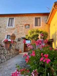 une maison en pierre avec des fleurs devant elle dans l'établissement Agriturismo La Sorgente di Rossi Valentino, à Larciano