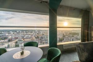 a table and chairs in a room with a large window at Sea Towers Panoramic Penthouse in Gdynia