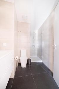 La salle de bains blanche est pourvue d'une douche et de toilettes. dans l'établissement Blue by the River 4 - Unique Penthouse Duplex with a View, à Lisbonne