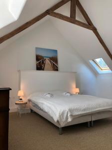 a bedroom with a white bed with two windows at merveilleux cottage dans parc de 7,5 hectares in Saint-Nicolas-du-Pélem