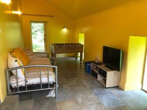 a living room with a bed and a television at merveilleux cottage dans parc de 7,5 hectares in Saint-Nicolas-du-Pélem