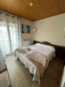 a bedroom with two beds and a wooden ceiling at Hotel Avet in La Coma i la Pedra