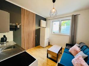 salon z niebieską kanapą i kuchnią w obiekcie Apartament Metro Center - Gdynia Centrum w mieście Gdynia